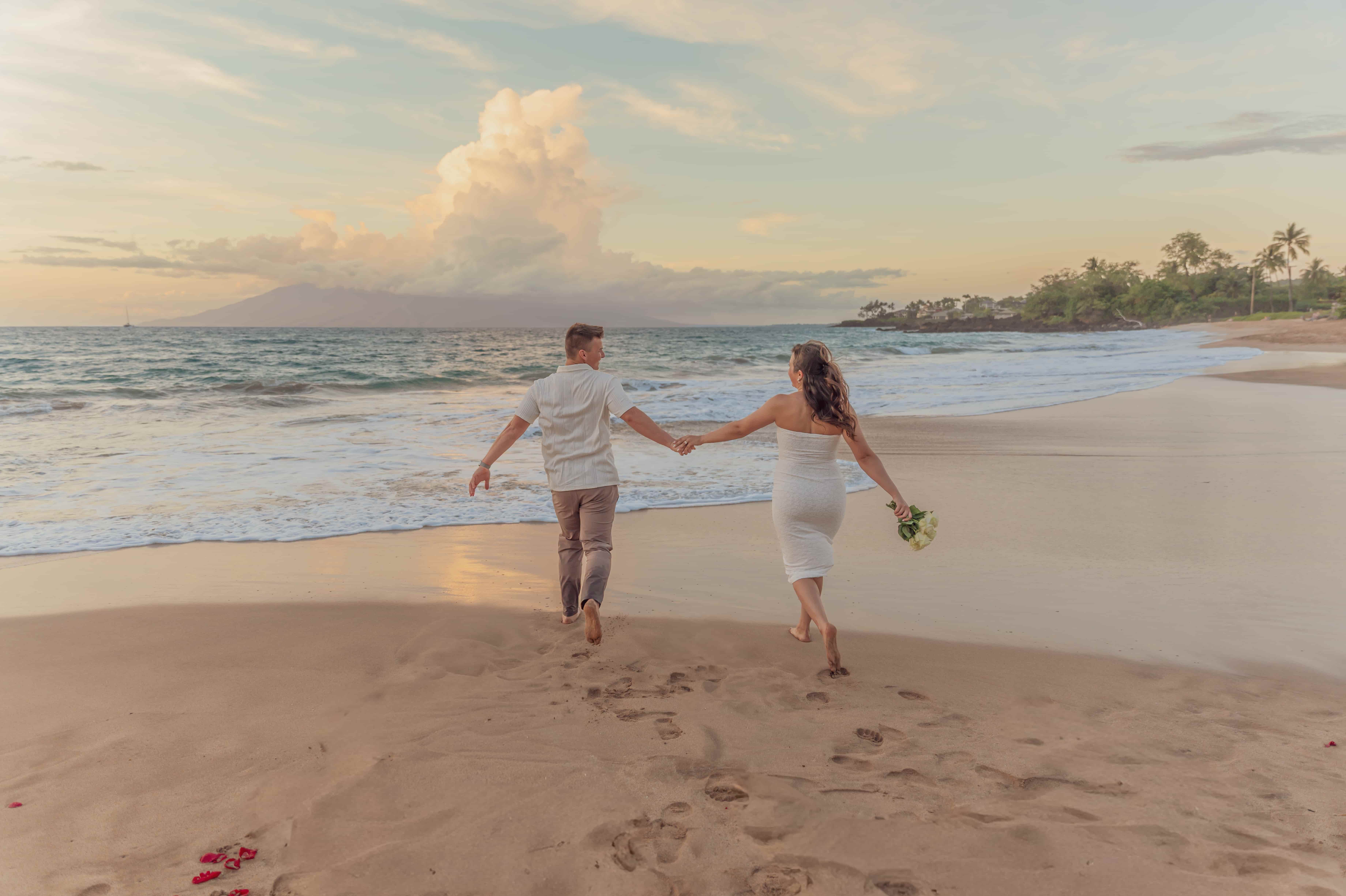 Engagement couple running into the ocean holding hands on a mini session in Maui