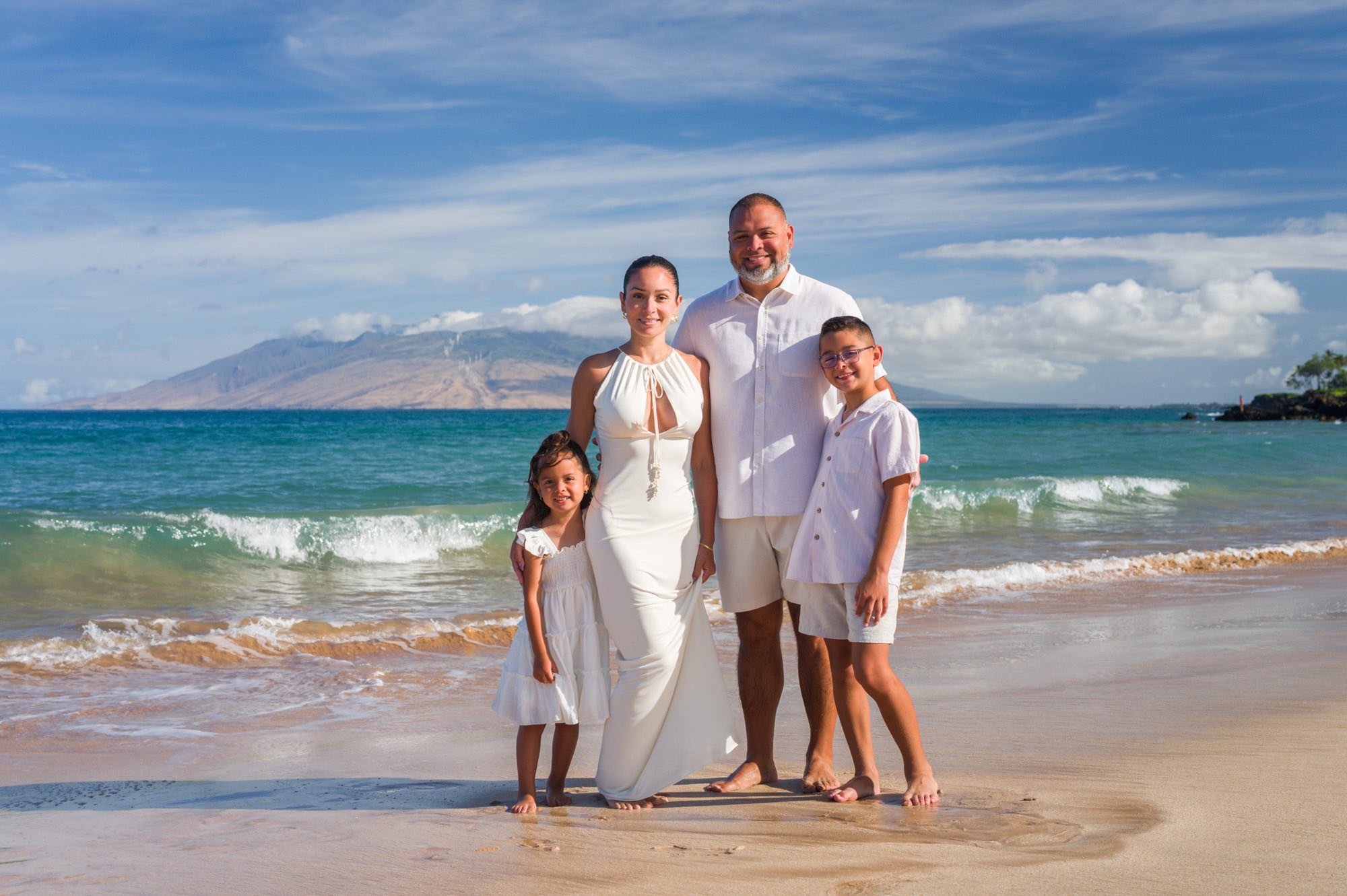 A family dressed in white beside vivid turquoise Maui water