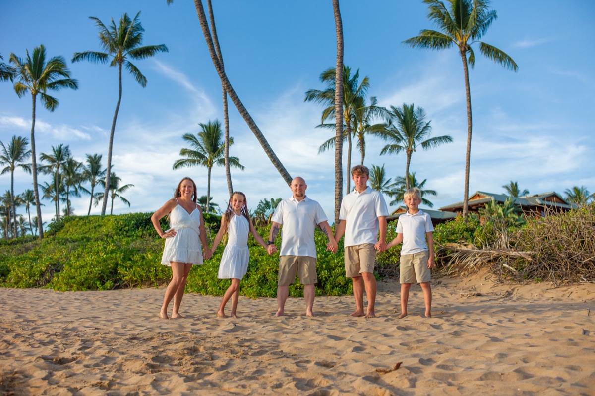 A family of five photographed beneath palm trees on a Maui beach