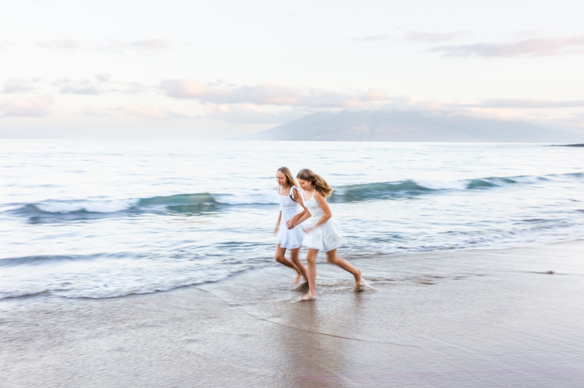 Two sisters running beside the ocean during a recent Maui session