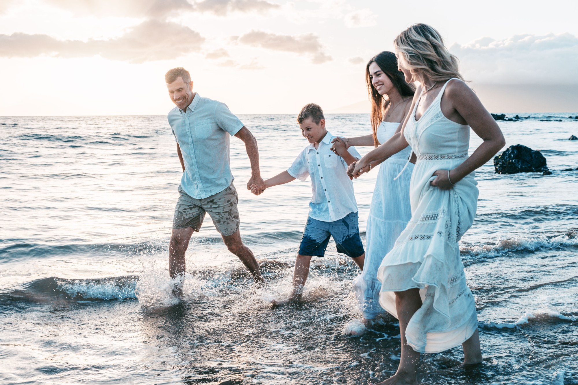 A family laughing together in the ocean at sunset