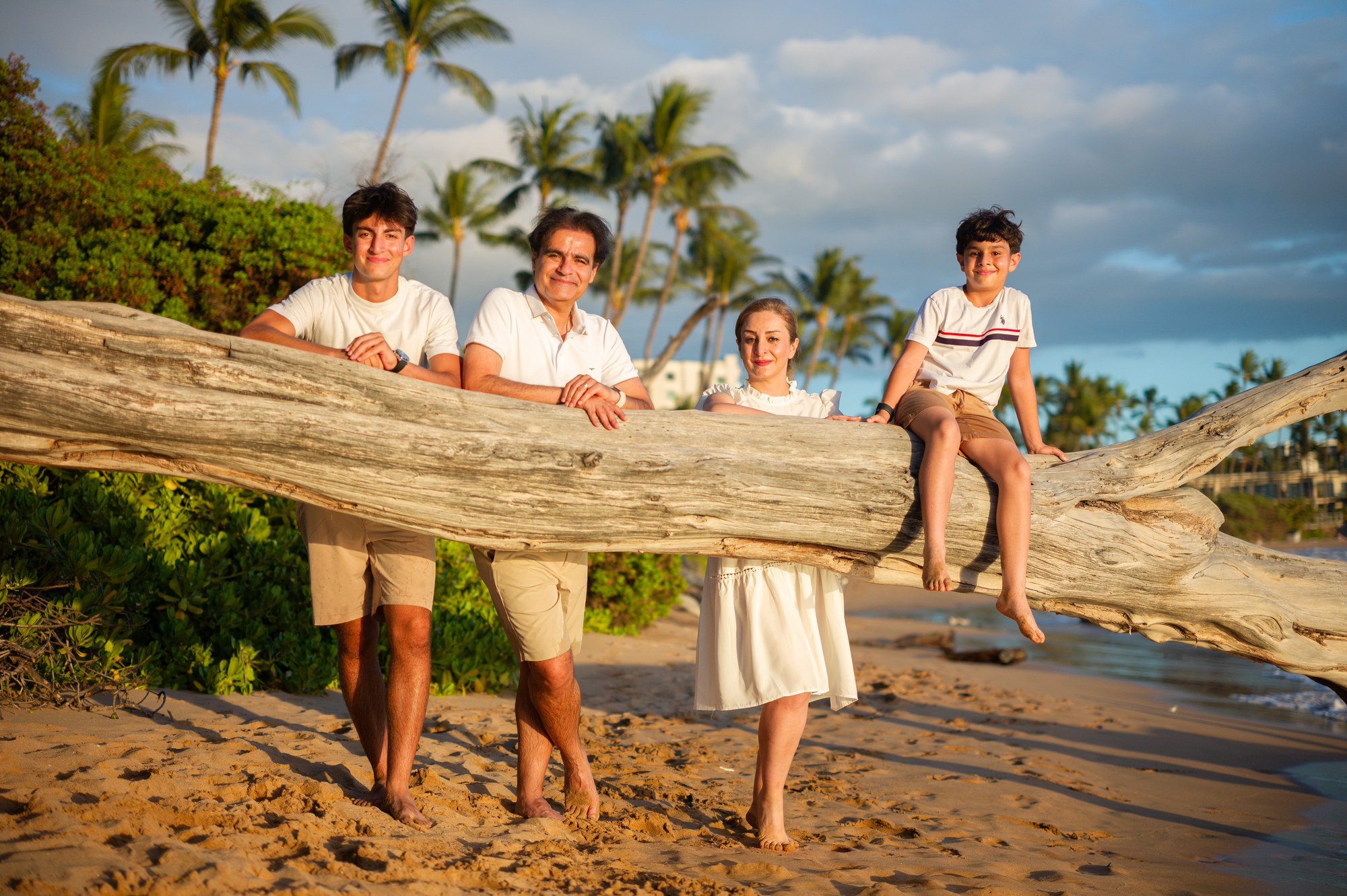 A family playing together beside a fallen tree on a Maui beach