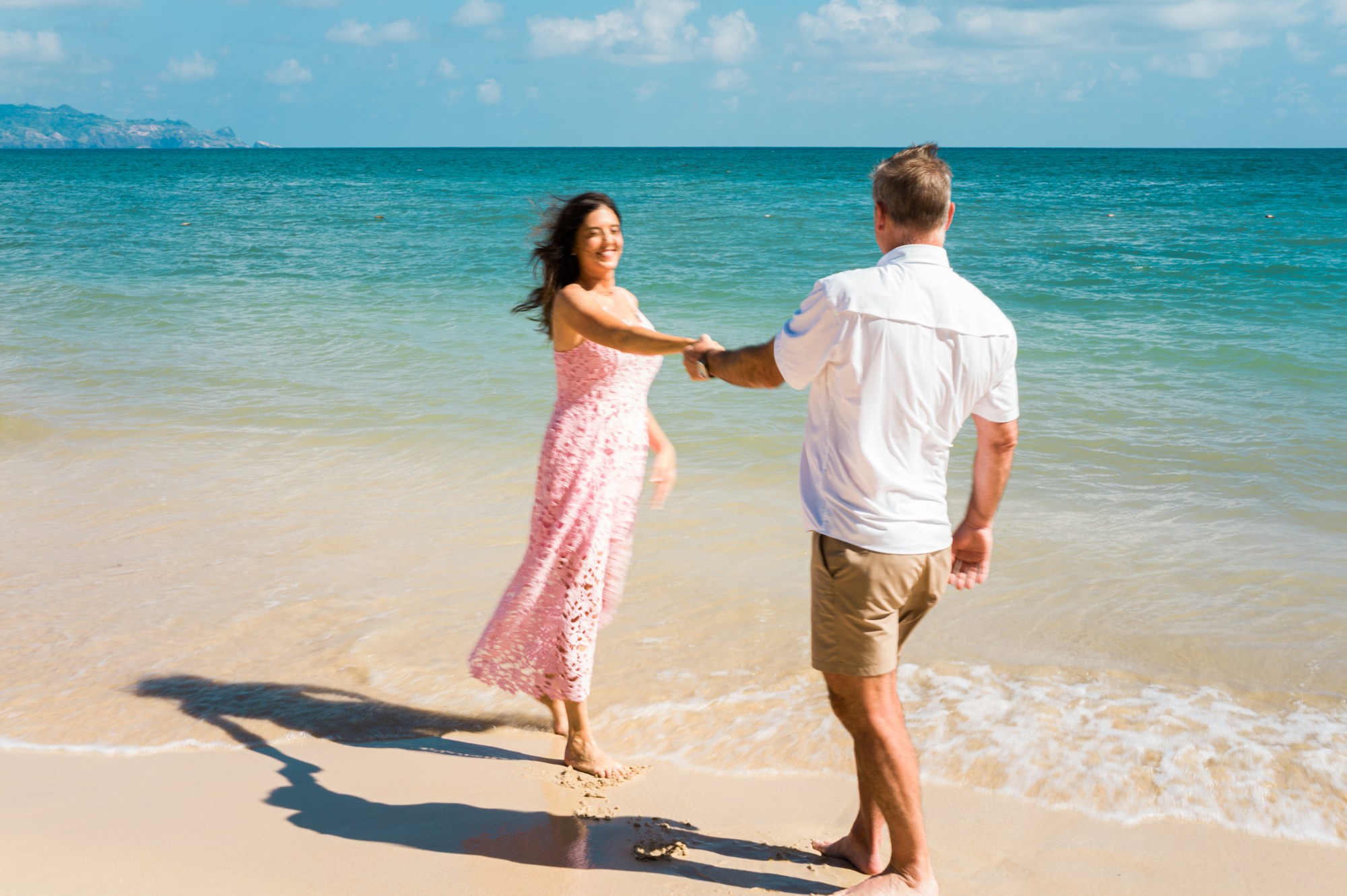 A couple photographed beside bright turquoise ocean water