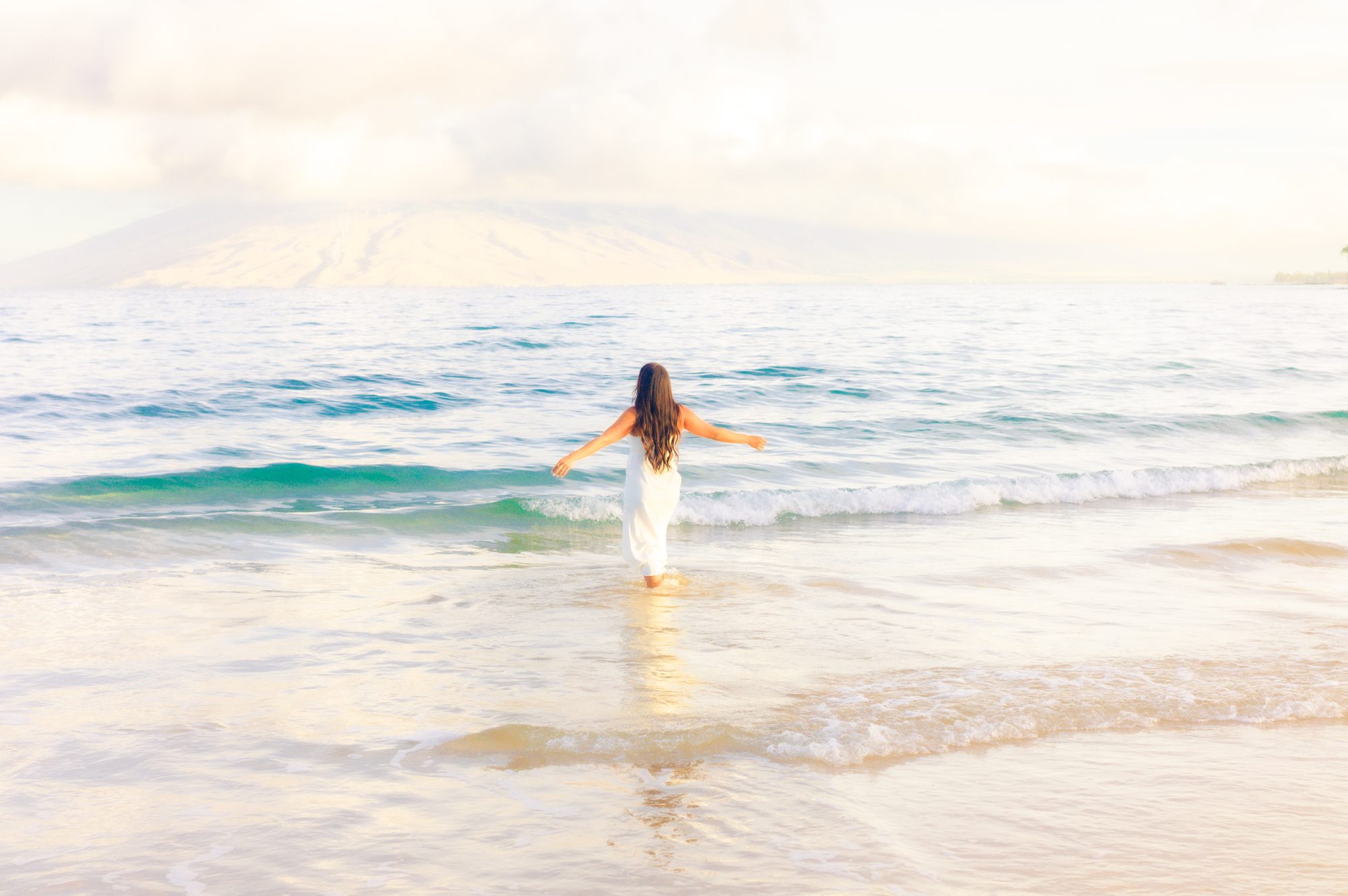 A family walking together on a Maui beach in soft morning light